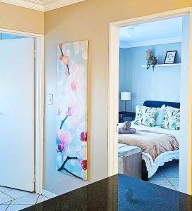 a bedroom with a bed with a painting of flowers at OCEAN VIEW, Blouberg Beach, Sunsets & Kite Beach in Bloubergstrand