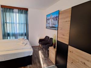 a hotel room with a bed and two chairs at Smart Wellness Hotel TREZOR in Pécs