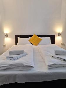 ein großes weißes Bett mit zwei Kissen und einem gelben Kissen in der Unterkunft Wellness Hotel TREZOR in Pécs