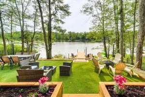 a lawn with chairs and tables next to a lake at Hot Tub and Game Room! Lakefront Gem in Pocono Mtns in Tobyhanna
