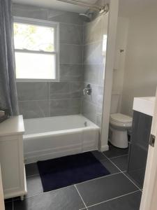 a bathroom with a white tub and a toilet at N Lake Ontario 3BR Home Near Beach Seabreeze in Rochester +27 photos