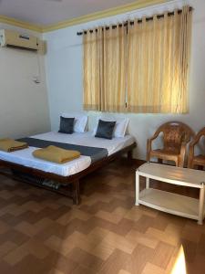 a bedroom with two beds and a chair and a table at Vartak wadi smita villa in Nagaon