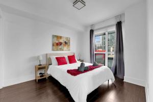 a white bedroom with a large white bed with red pillows at Lakeview Unit - sleeps 11 people near CN Tower Union Rogers Centre and Convention Centre in Toronto
