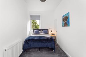 Un dormitorio con una cama con sábanas azules y una ventana. en Stylish Stay in Inverkeithing., en Fife