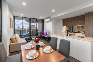 Una cocina y una sala de estar con mesa y sillas. en Modern 2BR Aprtmnt Fortitude Valley Prime Location, en Brisbane
