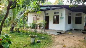 卡图纳耶克EECS Transit and Budget Homestay的一座小白色房子,拥有门廊和树木