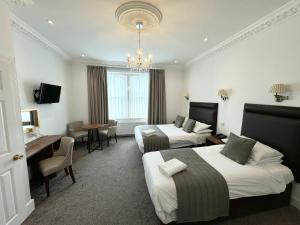 a hotel room with two beds and a desk at Sandyford Lodge in Glasgow