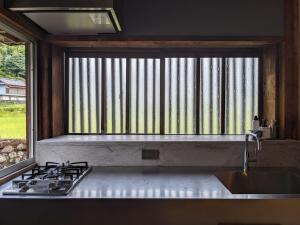 Una cocina con fregadero, estufa y ventana. en コワーキングスペース kuzume Base ゲストハウス 古朴-MOKU-1棟貸の宿, en Konan 16 fotos más