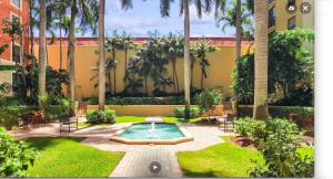 a courtyard with a swimming pool and palm trees at Downtown WPB Condo at the Square in West Palm Beach