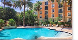 a swimming pool in front of a building with palm trees at Downtown WPB Condo at the Square in West Palm Beach