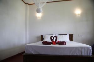 a bed with a pair of red towels on it at Hiruni Cottage Ella in Ella +15 photos