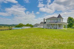 a large house on a grassy hill with a field at Sprawling Kentucky Getaway with Pool and Hot Tub! in Berry