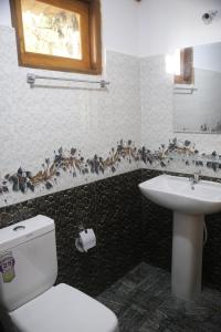 a bathroom with a toilet and a sink with birds on the wall at Hiruni Cottage Ella in Ella