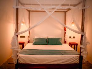 a bedroom with a canopy bed with two green pillows at Dutch House Hiriketiya in Dickwella +53 photos