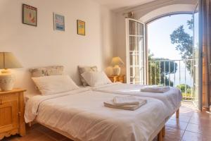 a bedroom with two beds and a large window at Villa D'arosa - Maison familiale provençale in Ramatuelle