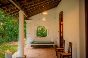 a porch with a bench and a painting on the wall at Dutch House Hiriketiya in Dickwella