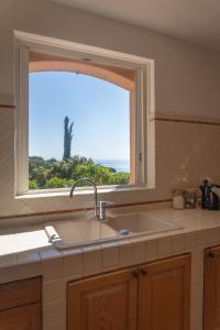 a kitchen sink and a window with a view of the ocean at Villa D'arosa - Maison familiale provençale in Ramatuelle
