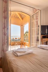 a bedroom with a large bed and a balcony at Villa D'arosa - Maison familiale provençale in Ramatuelle