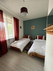 a bedroom with two beds and a window with red curtains at Manyana Guest House in Gyulagarak
