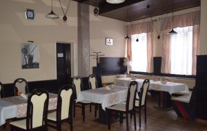 a dining room with white tables and chairs and a window at Ring Penzión in Komárno