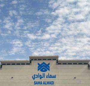 una señal en el lateral de un edificio con un cielo en SAMA ALWADi, en Wadi Al Dawasir