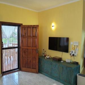 a living room with a television on a yellow wall at Fiocco di neve in Watamu