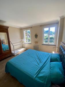 a bedroom with a blue bed and two windows at Gîte Massibel au coeur de Brassac in Brassac