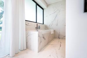 a white bathroom with a sink and a window at Villa L'oasis, piscine intérieur, extérieur sauna, cinéma in Mougins