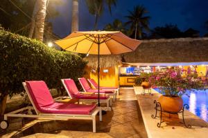 a group of chairs and an umbrella next to a pool at BEACH HOTEL INES en Zicatela in Brisas de Zicatela