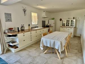 a kitchen with a table and a sink and a refrigerator at La Rose des Vents in Suzette