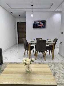 a dining room with a table and chairs and a vase of flowers at modern apartment in Tangier