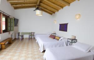 a room with three beds and a table and chairs at Posta de Purmamarca in Purmamarca