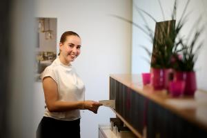 a woman standing next to a counter holding a piece of paper at Hotel Gasthof Krönele in Lustenau