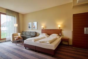 a bedroom with a large bed and a couch at Hotel Gasthof Krönele in Lustenau +137 photos