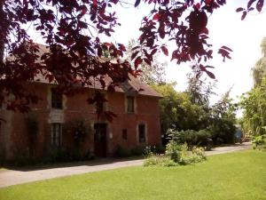 an old red brick house with a green yard at La Ferme Des Vignes in Hotot-en-Auge
