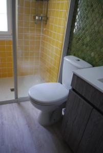 a bathroom with a toilet and a shower with yellow tiles at La caburoche de Charlemagne in Civray-de-Touraine