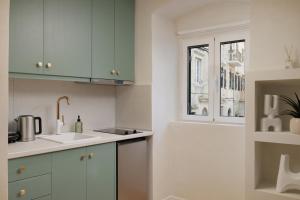 eine weiße Küche mit Spüle und Fenster in der Unterkunft Dousmani Old Town Studio in Korfu-Stadt + 25 Fotos