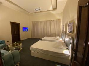 a hotel room with two beds and a couch at Hidden Paradise Villa in Naj‘ al Aḩwāl