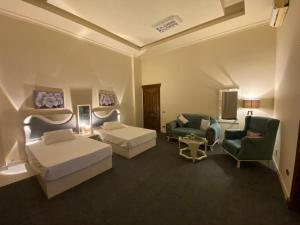 a hotel room with two beds and a chair at Hidden Paradise Villa in Naj‘ al Aḩwāl +26 photos