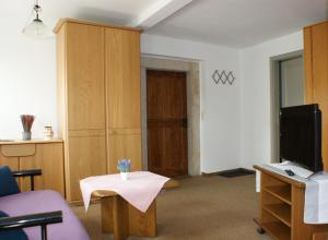 ein Wohnzimmer mit einem Tisch und einem TV in der Unterkunft Pension Goldener Anker in Reinhardtsdorf