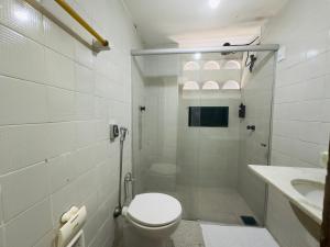 a white bathroom with a toilet and a sink at Barrudada Residence in Fortaleza