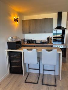 a kitchen with a counter with two white chairs at Élégant T2 acces direct plage in Saint-Cyprien-Plage +1 photo