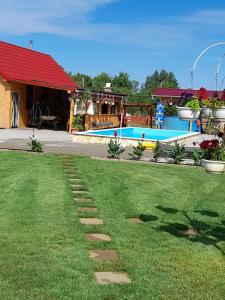 a grassy yard with a swimming pool and a house at Hobby Vendégház in Kiskunmajsa