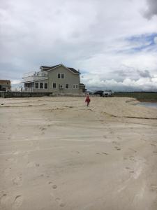 una persona caminando por la playa frente a una casa en Private Beach Front house Newport, New Jersey, 