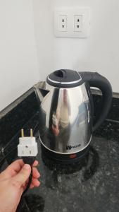 a person holding a tea kettle with a picture on it at Hospedaje Santa Sofia Minga Guazú in Minga Guazú