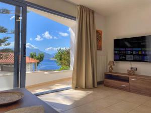 een woonkamer met een groot raam met uitzicht op het water bij GN apartment in Ayia Evfimia