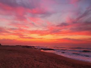 a sunset on a beach with the ocean at The Beaches in Umtentweni +1 photo