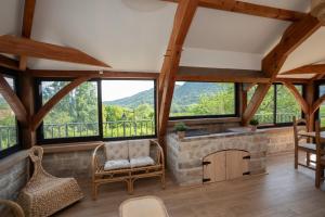 a living room with a fireplace and large windows at Havre de paix au coeur du Bugey in Magnieu