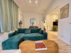 Una sala de estar con un sofá azul y una mesa. en Suite Madeleine - Cœur Historique, en Béziers