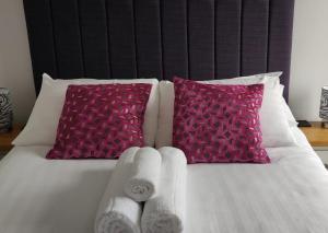 a bed with two towels and two pink pillows at Luxury Sea View Apartment - One Bedroom in Aberystwyth